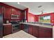 A kitchen with cherry wood cabinets, stainless steel appliances, and light countertops, with a view into the adjacent room at 34448 Tuscany Ave, Sorrento, FL 32776