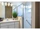 Bathroom with single sink vanity, plant, and shower with glass doors at 3603 Eversholt St, Clermont, FL 34711