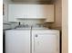 Well-lit laundry room with a side-by-side washer and dryer, and overhead cabinets at 3827 Westerham Dr, Clermont, FL 34711