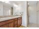Bathroom featuring double sinks, wood cabinets, and a tiled walk-in shower with grab bars at 5829 Tupelo Ter, The Villages, FL 32163