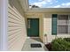 Inviting front entrance with a green door, beige siding and matching shutters at 604 Juanita Ct, The Villages, FL 32159