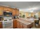 Well-lit kitchen with laminate countertops, wood cabinets, and a convenient breakfast bar overlooking the living area at 7650 Se 174Th Gaillard Pl, The Villages, FL 32162