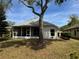 View of the backyard featuring a screened-in porch area, mature trees, and green lawn at 8165 Bridgeport Bay Cir, Mount Dora, FL 32757