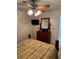 Cozy bedroom featuring a dark wooden dresser, mirror, ceiling fan with lights and a bed at 8165 Bridgeport Bay Cir, Mount Dora, FL 32757