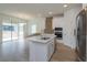 Bright kitchen featuring an island with sink, stainless steel appliances, white cabinets, and wood-look flooring at 990 Fiesta Key Cir, Lady Lake, FL 32159