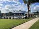 Community pool and solar shade structure surrounded by lush landscaping, palm trees and manicured lawn at 990 Fiesta Key Cir, Lady Lake, FL 32159