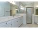 Bathroom featuring quartz countertops, double vanity, white cabinets, and glass shower with marble tile at 995 Fiesta Key Cir, Lady Lake, FL 32159