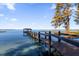 The long dock stretches across the water, under a sunny blue sky, leading to a charming covered boathouse at 15749 Acorn Cir, Tavares, FL 32778