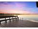 Waterfront dock featuring bench seating, ladder access, and stunning views of the serene lake at sunset at 15749 Acorn Cir, Tavares, FL 32778