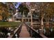 Grand waterfront home with a private dock, lush trees, and manicured lawns at 15749 Acorn Cir, Tavares, FL 32778