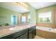 A well-lit bathroom offers dual sinks, a soaking tub, and a glass-enclosed shower at 2572 Limerick Cir, Grand Island, FL 32735