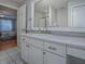 Bathroom vanity with white cabinets, large mirror, and view of bedroom at 3360 Richmond Dr, The Villages, FL 32162
