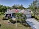 Charming single-story home with well-maintained landscaping, an attached garage, and an American flag at 3360 Richmond Dr, The Villages, FL 32162