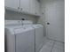 Functional laundry room features side-by-side washer and dryer, storage cabinets, and tiled flooring at 3360 Richmond Dr, The Villages, FL 32162