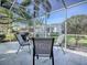 Enjoy this screened-in patio with ample seating and a view of the manicured backyard and grill at 3360 Richmond Dr, The Villages, FL 32162