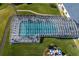 Aerial view of a large enclosed swimming pool surrounded by lush landscaping in a residential community at 5441 Sea Leopard St, Tavares, FL 32778