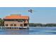 Beautiful waterfront home on stilts, featuring a copper-colored roof, with private dock and boat, and an airplane overhead at 5441 Sea Leopard St, Tavares, FL 32778