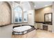 Luxurious bathroom featuring a soaking tub with marble accents, an arched window, and a vanity area at 10417 Lake Louisa Rd, Clermont, FL 34711