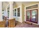 Inviting front porch with brick columns, windows, and a stylish front door with glass accents at 10417 Lake Louisa Rd, Clermont, FL 34711
