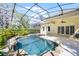 Sparkling pool with rock features under a screened enclosure, surrounded by a well-maintained patio at 10417 Lake Louisa Rd, Clermont, FL 34711