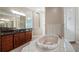 Well-lit bathroom with a soaking tub, separate shower, and granite countertop vanity at 10651 Arrowtree Blvd, Clermont, FL 34715