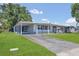 Exterior view of a single-story home with a driveway, lawn, and covered carport at 1112 Elkhart Cir, Tavares, FL 32778