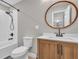 Bathroom featuring shower-tub combo with wood vanity, round mirror, and white subway tile at 11619 Lane Park Rd, Tavares, FL 32778