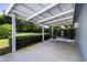 Covered carport area with white support beams and concrete floor and a hedge row nearby at 11619 Lane Park Rd, Tavares, FL 32778