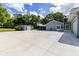 Expansive concrete driveway and neutral gray exterior with mature trees and landscaping at 11619 Lane Park Rd, Tavares, FL 32778