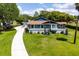 Well-maintained home with lush green lawn, mature landscaping, and a concrete driveway at 11619 Lane Park Rd, Tavares, FL 32778