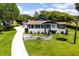 Charming single-story home boasts a well-maintained lawn and a long driveway, framed by lush greenery and mature trees at 11619 Lane Park Rd, Tavares, FL 32778