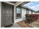 Charming front entry with a gray six-panel door, decorative stone, and neatly trimmed bushes at 12370 Se 100Th Ct, Belleview, FL 34420