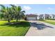 Long driveway with a palm tree, leading to a one-car garage in a verdant neighborhood at 1310 Leone Ln, The Villages, FL 32159