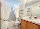Bright bathroom with a shower-tub combo, oak vanity, and a decorative mirror at 1407 Island Cove Dr, Deland, FL 32724