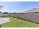 A spacious backyard with a well-maintained lawn, privacy wall and a small patio area at 1589 Armstrong Ave, The Villages, FL 32163