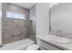 Well lit bathroom featuring grey tiled shower with a white bathtub and window at 1589 Armstrong Ave, The Villages, FL 32163