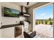 Outdoor kitchen with a built-in grill, fridge, and TV on a covered patio with an outdoor view at 16028 Trivoli Cir, Montverde, FL 34756