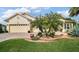 Charming home featuring manicured landscaping, a brick driveway, a two-car garage, and elegant palm trees at 17066 Se 111Th Ter, Summerfield, FL 34491