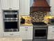 Gourmet kitchen boasts stainless appliances, double oven, gas range, and custom backsplash at 17066 Se 111Th Ter, Summerfield, FL 34491