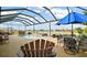 Relaxing screened pool area with hot tub, pond view and a table with a large umbrella at 17066 Se 111Th Ter, Summerfield, FL 34491