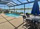 Relaxing screened pool area with hot tub, pond view, and outdoor dining area with chairs at 17066 Se 111Th Ter, Summerfield, FL 34491