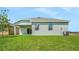The backyard offers a spacious lawn with a covered patio, windows, and lush greenery at 179 Bottle Brush Dr, Haines City, FL 33844