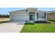 Charming single-Gathering home with a well-manicured lawn, gray exterior, and an attached two-car garage at 179 Bottle Brush Dr, Haines City, FL 33844