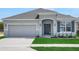 Charming single-Gathering home with a well-manicured lawn, gray exterior, and an attached two-car garage at 179 Bottle Brush Dr, Haines City, FL 33844