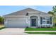 Charming single-Gathering home with a well-manicured lawn, gray exterior, and an attached two-car garage at 179 Bottle Brush Dr, Haines City, FL 33844