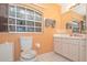 Bright bathroom with marble-look toilet seat, ample cabinet space, and large window at 202 N Palm Ave, Howey In The Hills, FL 34737