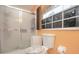 Bathroom features a toilet, frosted glass shower, and window at 202 N Palm Ave, Howey In The Hills, FL 34737