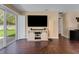 Living room features hardwood floors, TV on console table and glass sliding doors to backyard at 20816 Sullivan Ranch Blvd, Mount Dora, FL 32757
