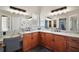 Bathroom vanity featuring dual sinks, wood cabinets, granite countertops, and framed mirrors at 2142 Margarita Dr, The Villages, FL 32159