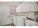 Well-equipped laundry room with modern washer, dryer, utility sink, and storage at 2142 Margarita Dr, The Villages, FL 32159